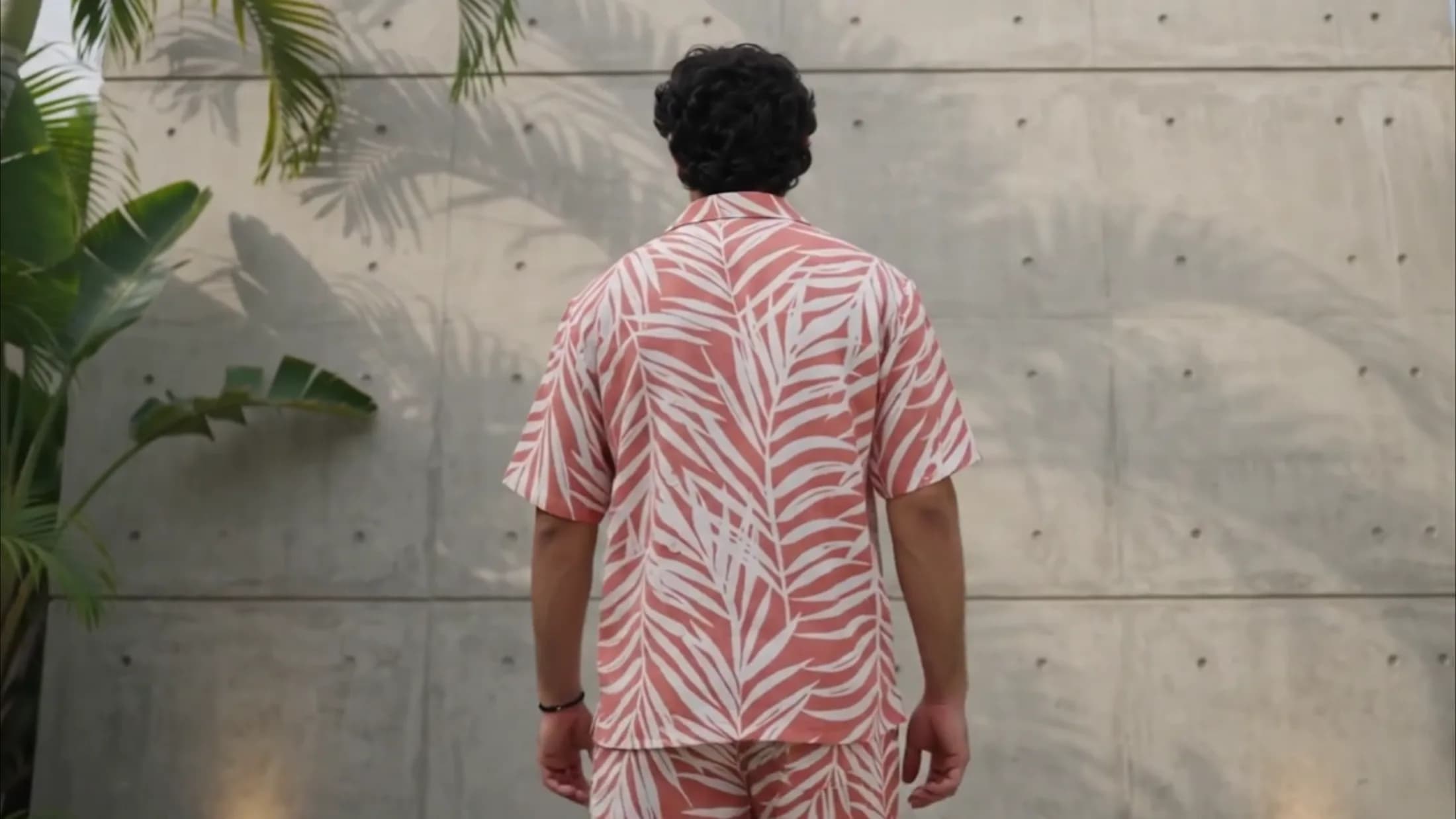 The palm print co-ord set worn against a concrete wall, palm fronds and their shadows across it