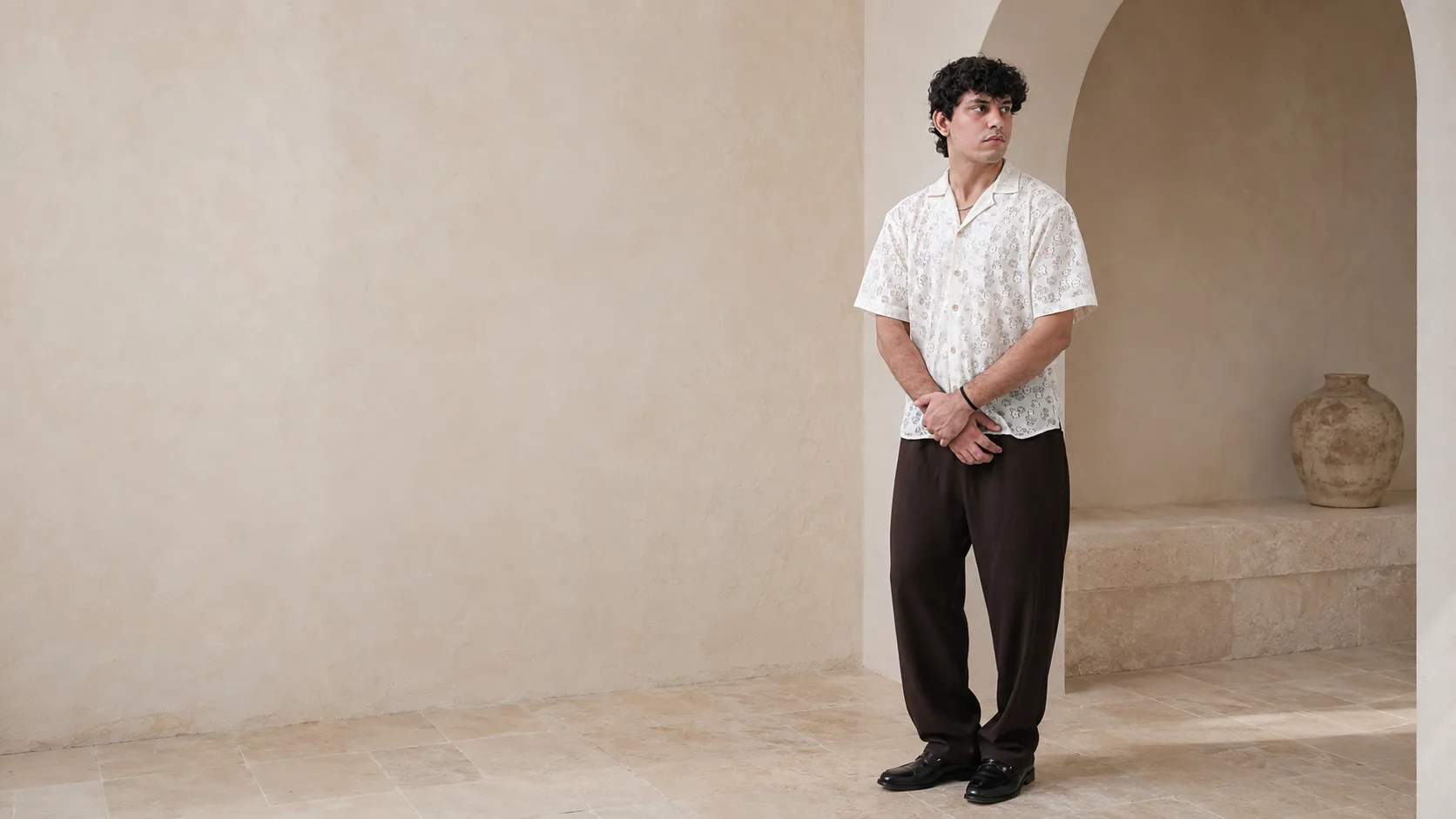 Model wearing the RIZONÉ eyelet floral camp collar shirt in ivory with espresso relaxed trousers